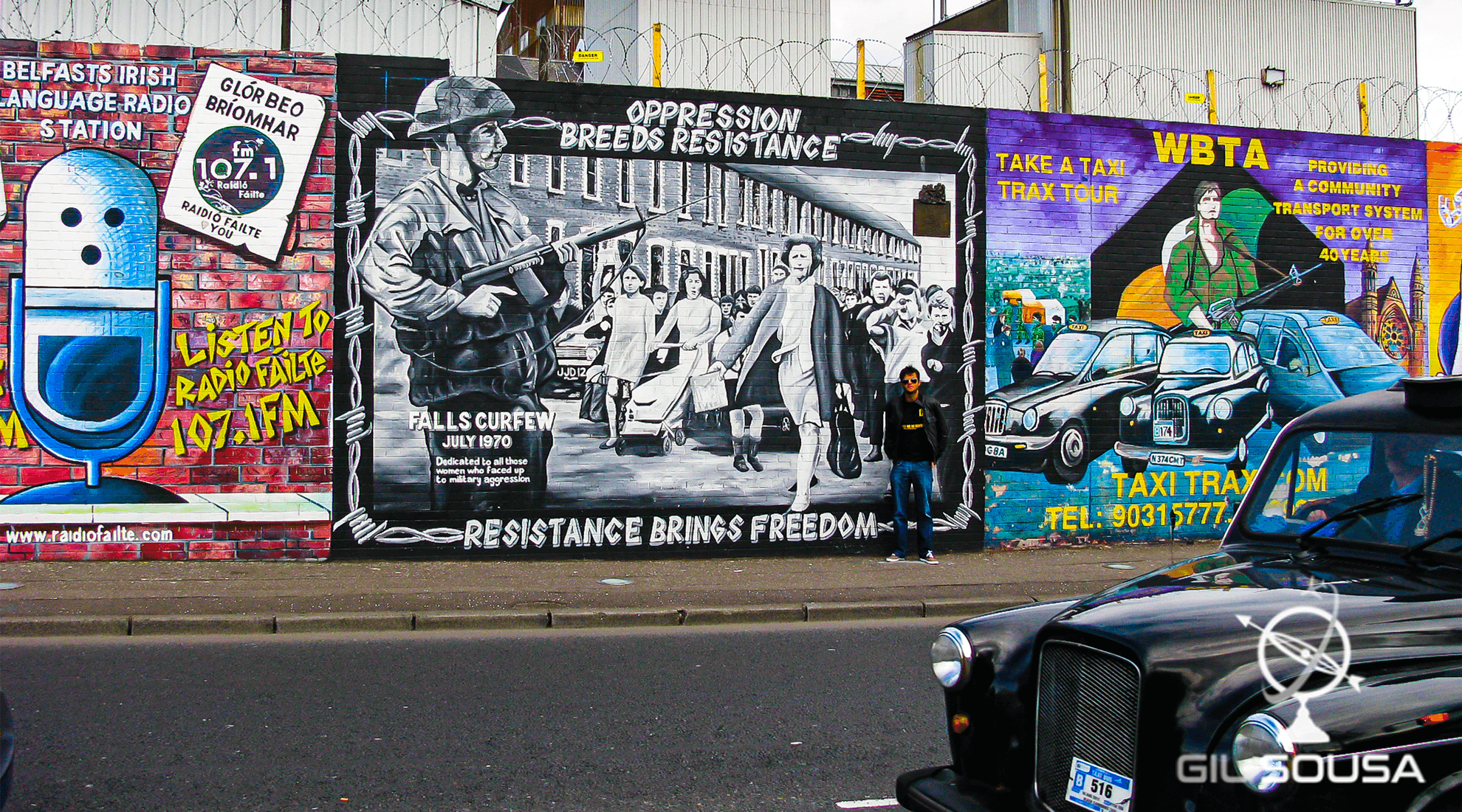 Back taxi next to one of the Peace Wall's section in Belfast